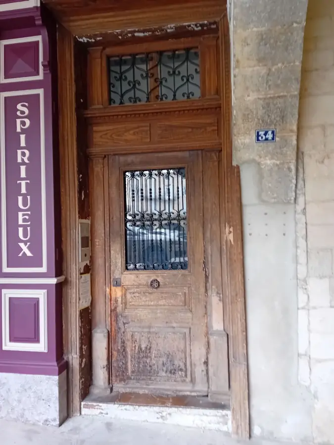 Porte ancienne en bois et encadrement en pierre sur la place des Arcades à Nyons.