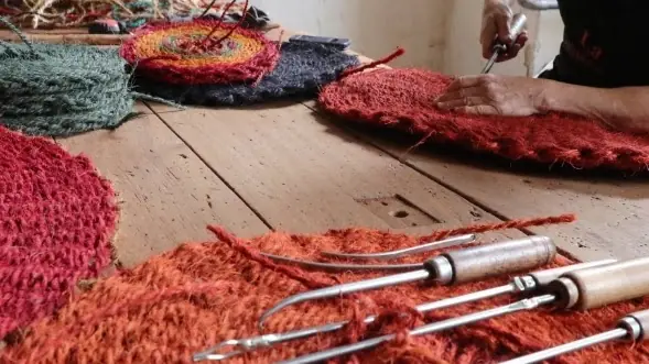 Scourtins rouges et aiguilles métalliques posés sur une table de l’atelier.