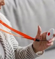 Une personne tient le bouton rouge d’un pendentif de téléassistance.